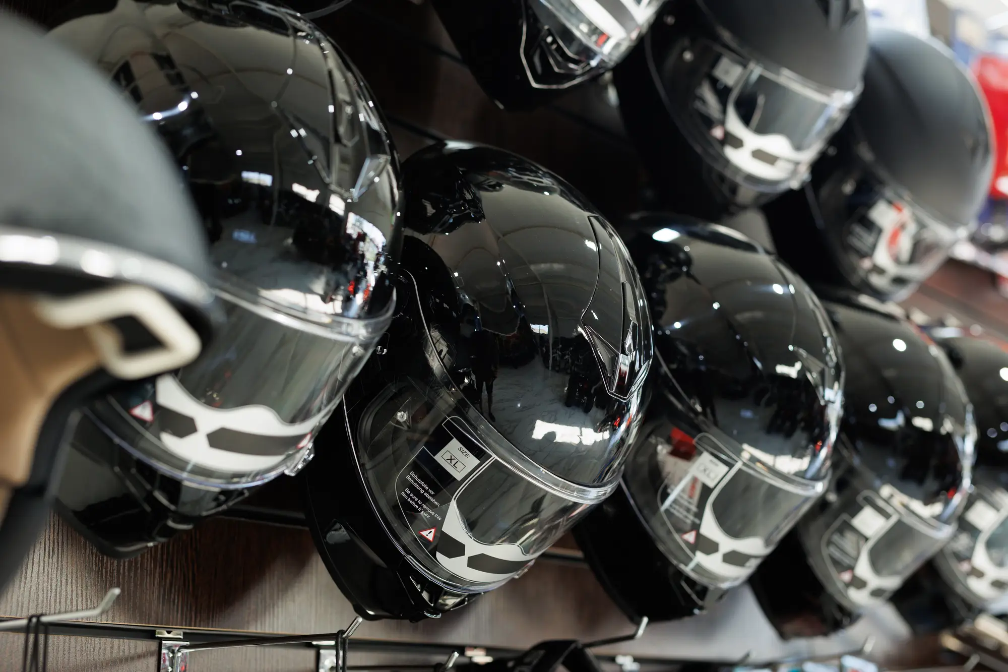 Rows of glossy black full-face helmets on display in a shop