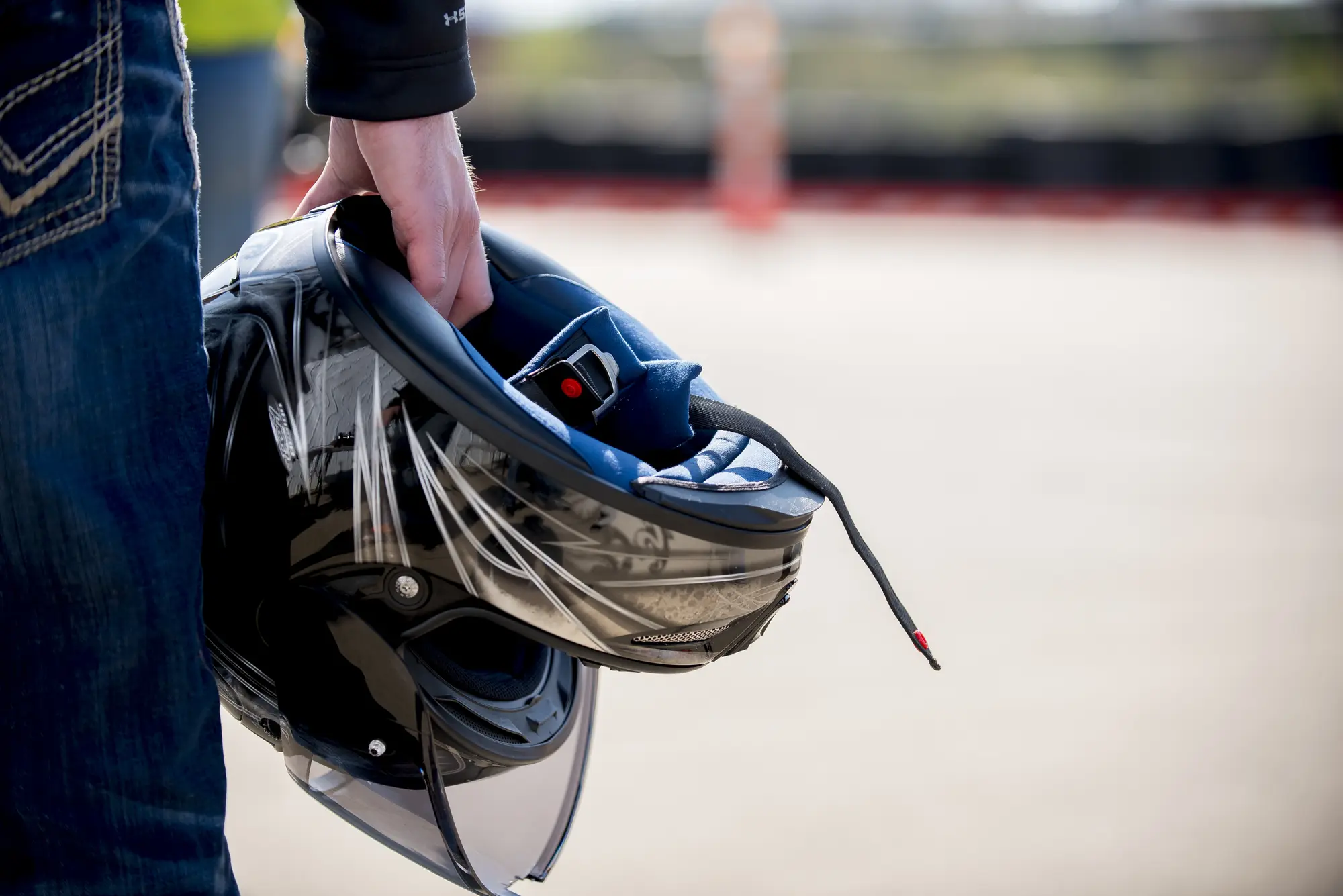 A man holding a shiny black motorcycle helmet by his side